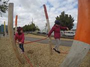 Zwei Mädchen balancieren auf Seilen auf dem Spielplatz des Außengeländes der Tagesstätte.